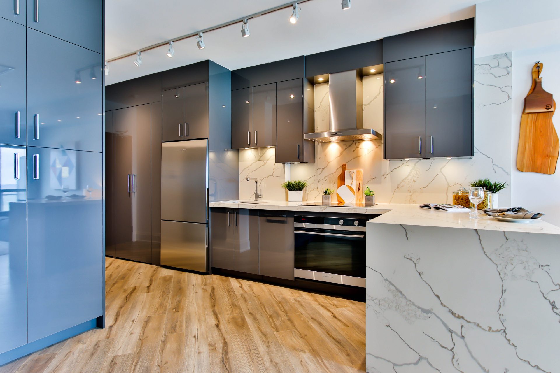 Kitchen with wood floor, black and blue cabine and a marble counter and backsplash